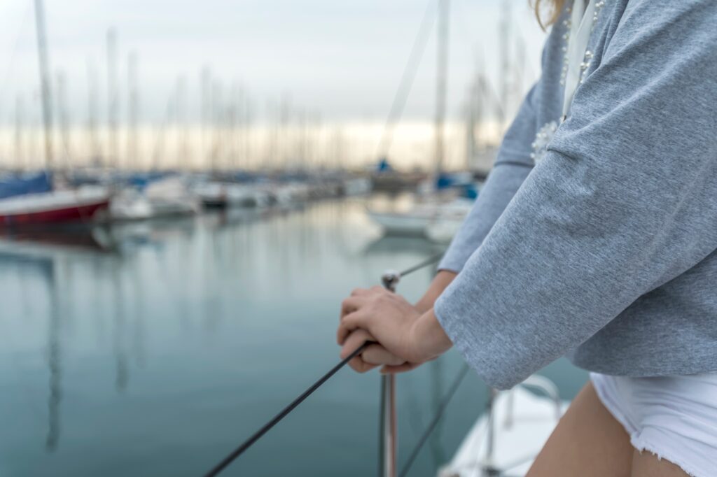 Closeup of a woman hand holding boat railing in yacht marina